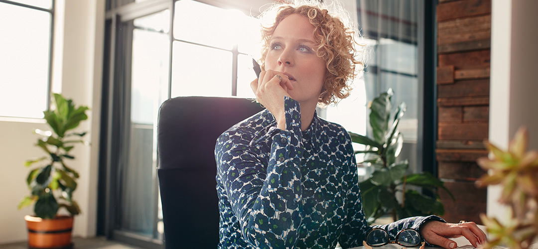 blog-employee_at_desk-1080x500 A young woman sitting at an office desk