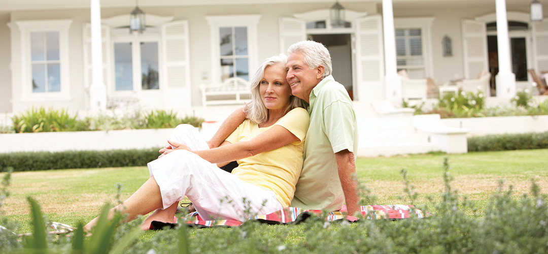 blog-featured_retirement-risk_1080x500 A mature couple sits on a blanket in front of a house