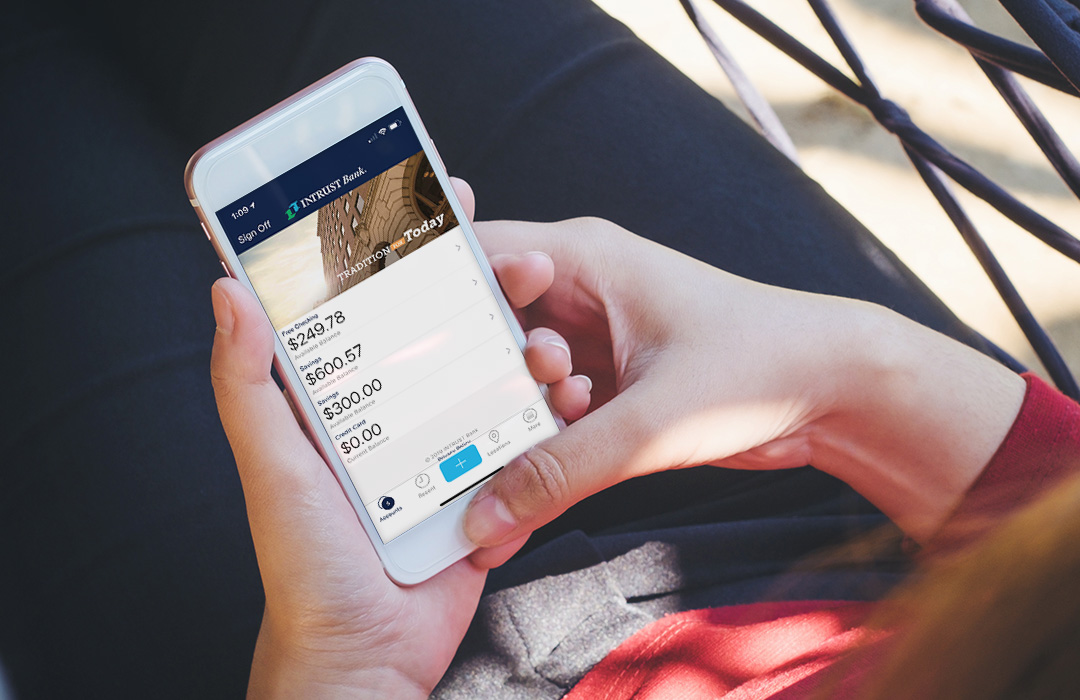 photo-mobile_banking_2020-1080x700 A woman holding an iPhone using the INTRUST Mobile Banking app