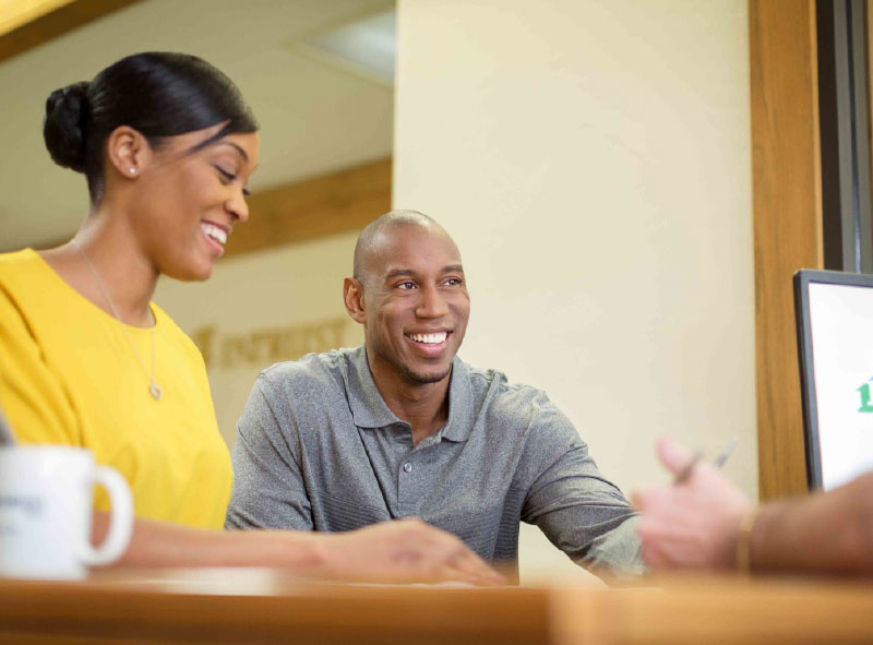 Smiling couple sitting at a desk in a banking center