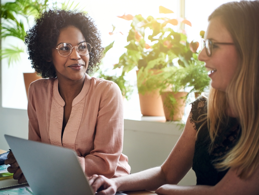 Two women working on a laptop in an office
