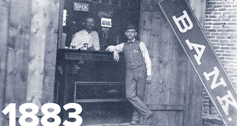 Black and white photo of person standing in front of bank teller